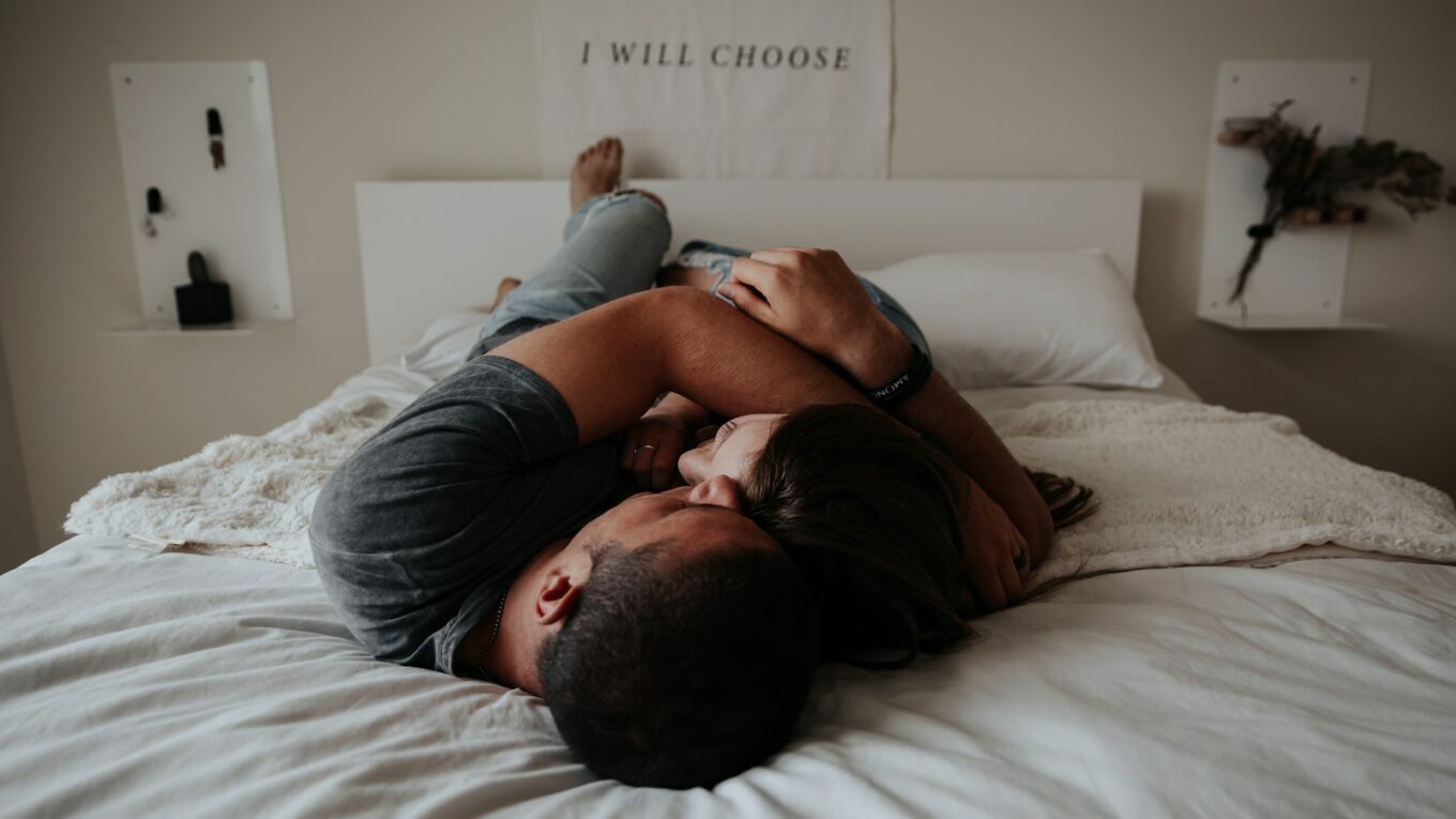 A man and woman cuddling together in bed.